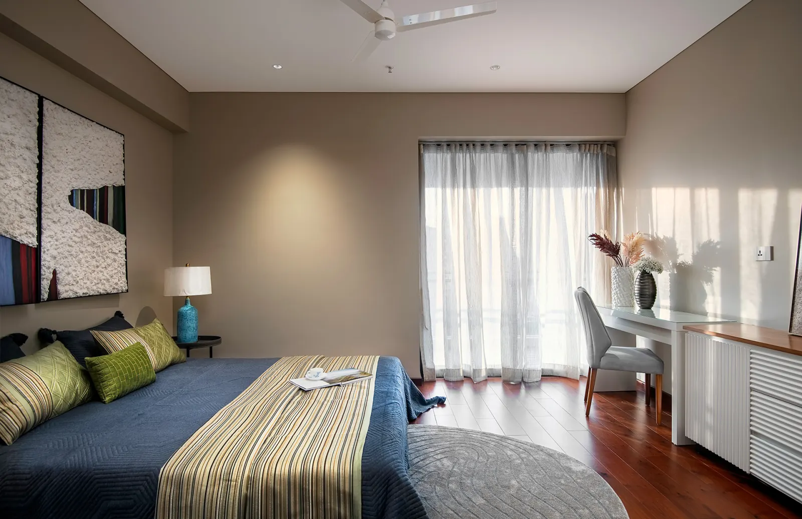 A guest bedroom with layered bedding and a writing desk by the window