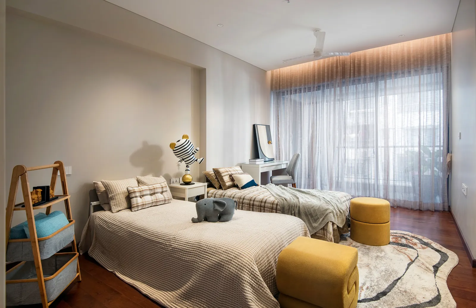 A bedroom with a study desk set against floor-to-ceiling windows